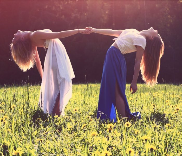 two_women_bending_while_holding_hands